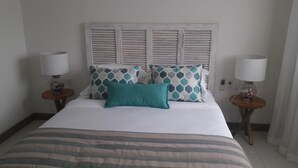 A hotel room with a bed, two bedside tables, and a headboard with shutters. - L'escale Beachfront Luxury Suite By Dream Escapes (Black River)