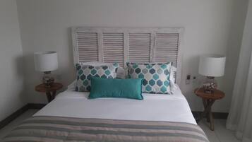 A hotel room with a bed, two bedside tables, and a headboard with shutters.