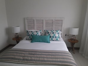 A hotel room with a bed, two bedside tables, and a headboard with shutters. - L'escale Beachfront Luxury Suite By Dream Escapes (Black River)