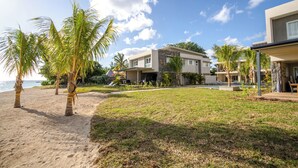 A beachfront property with a pool, palm trees, and a modern building with multiple balconies. - L'escale Beachfront Luxury Suite By Dream Escapes (Black River)