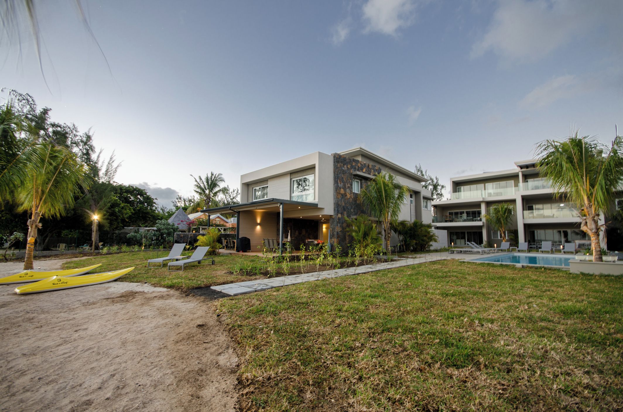 A modern hotel with a pool, outdoor seating, and a well-maintained lawn.