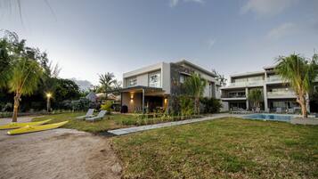 A modern hotel with a pool, outdoor seating, and a well-maintained lawn.