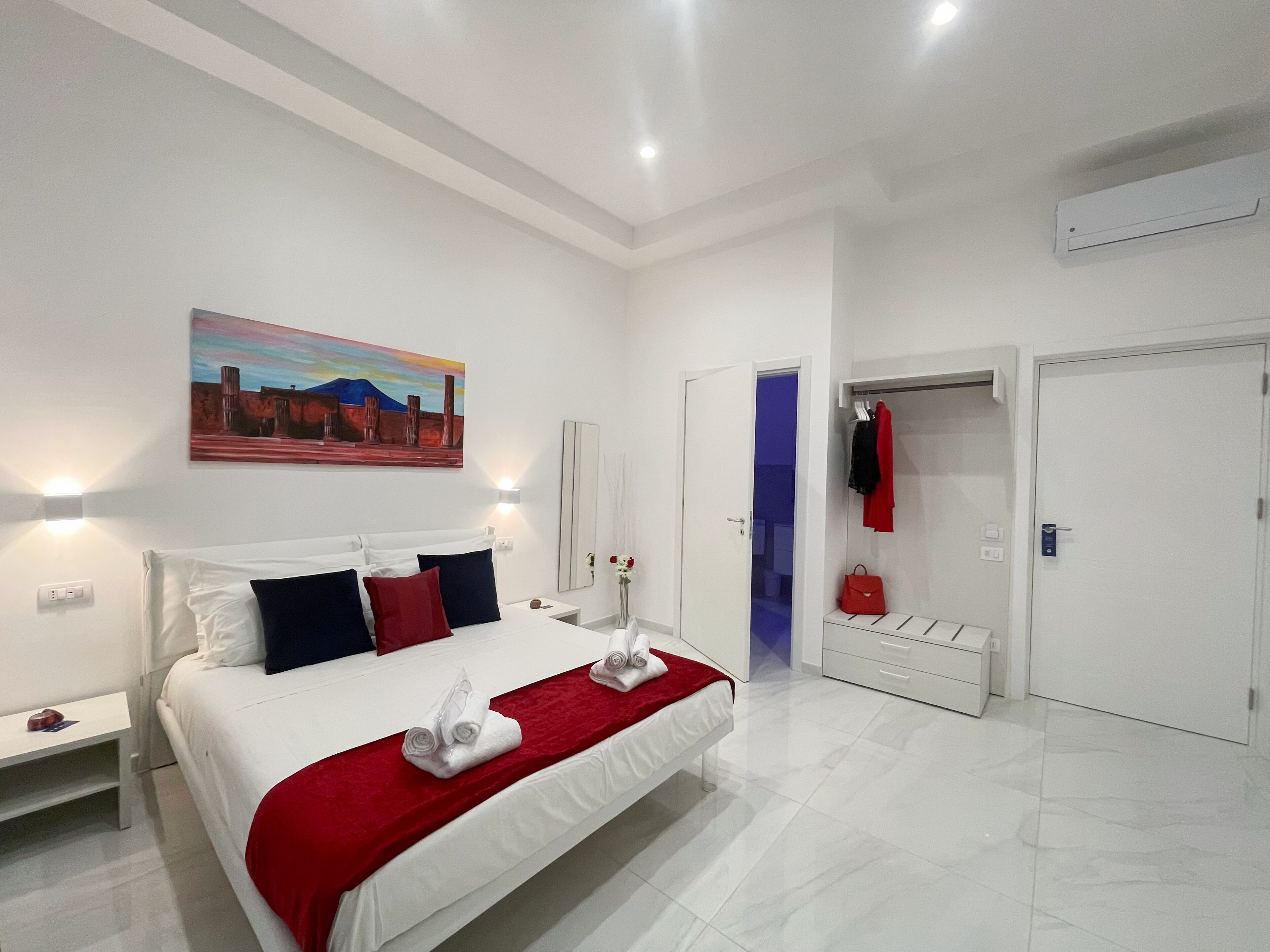 Una habitación de hotel moderna con una cama grande, un cuadro en la pared y un vestidor.