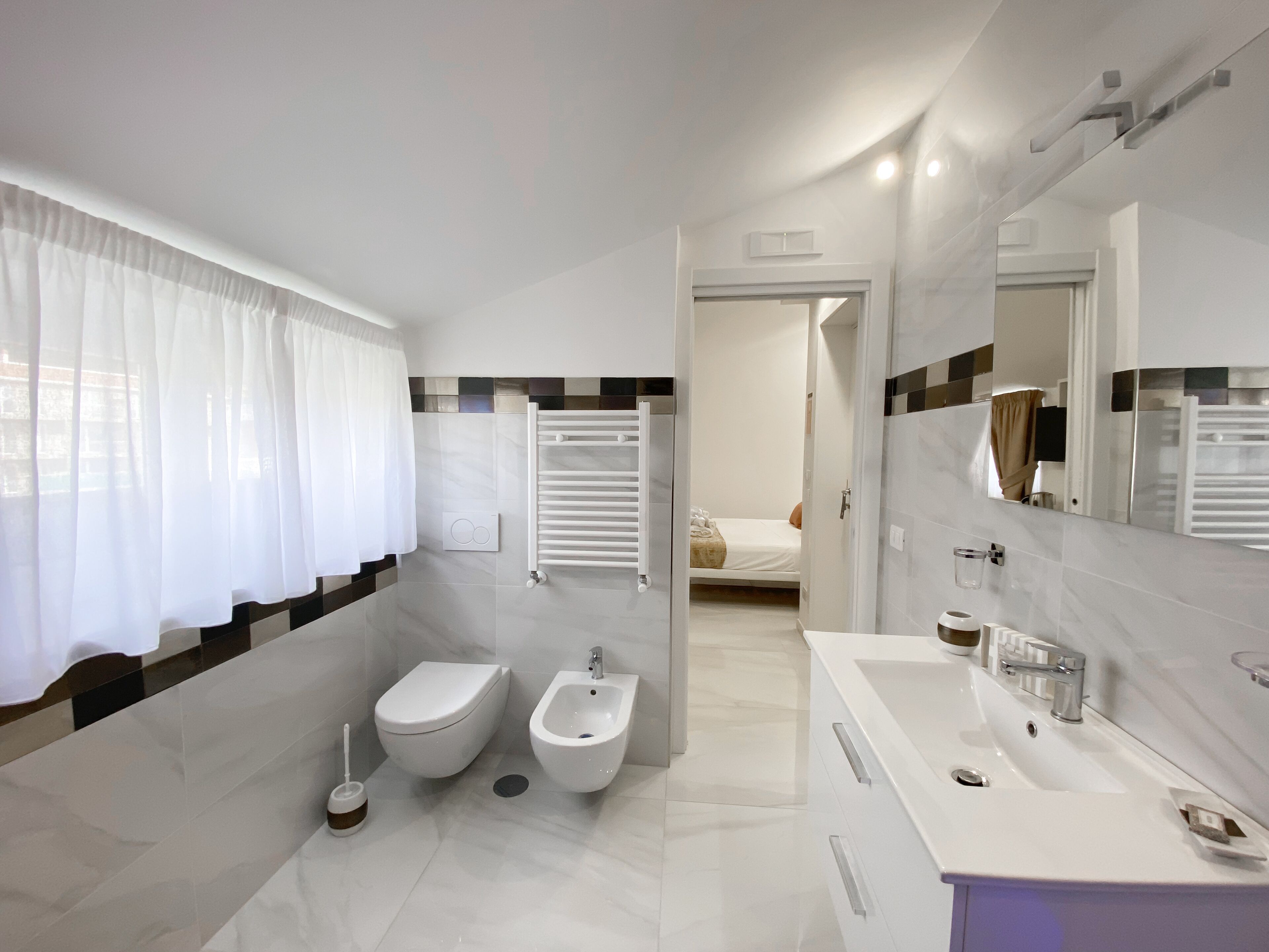 Un baño moderno con inodoro, bidé y lavamanos. Se ve una zona de ducha al fondo.