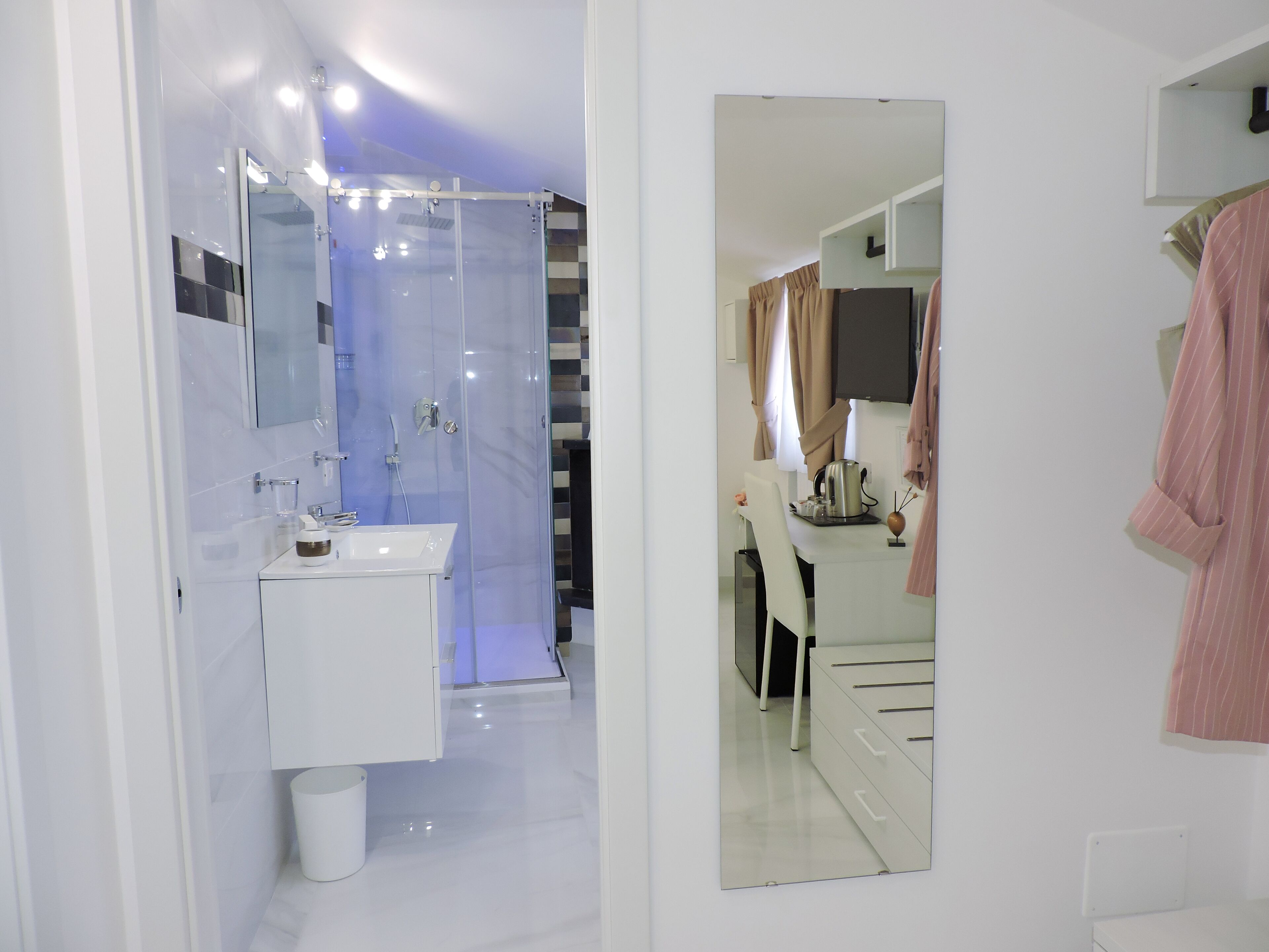A modern bathroom with a glass shower enclosure, a white sink, and a mirror reflecting the room.
