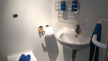 A bathroom with a toilet, sink, and a mirror.