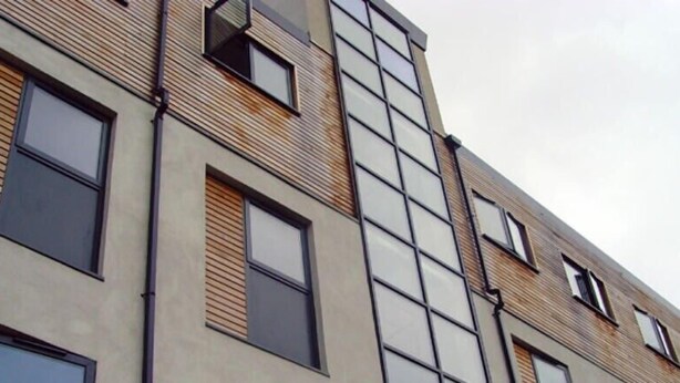 Un immeuble à plusieurs étages doté d’une architecture moderne, caractérisé par de grandes fenêtres et une combinaison de matériaux, notamment de la brique et du béton.
