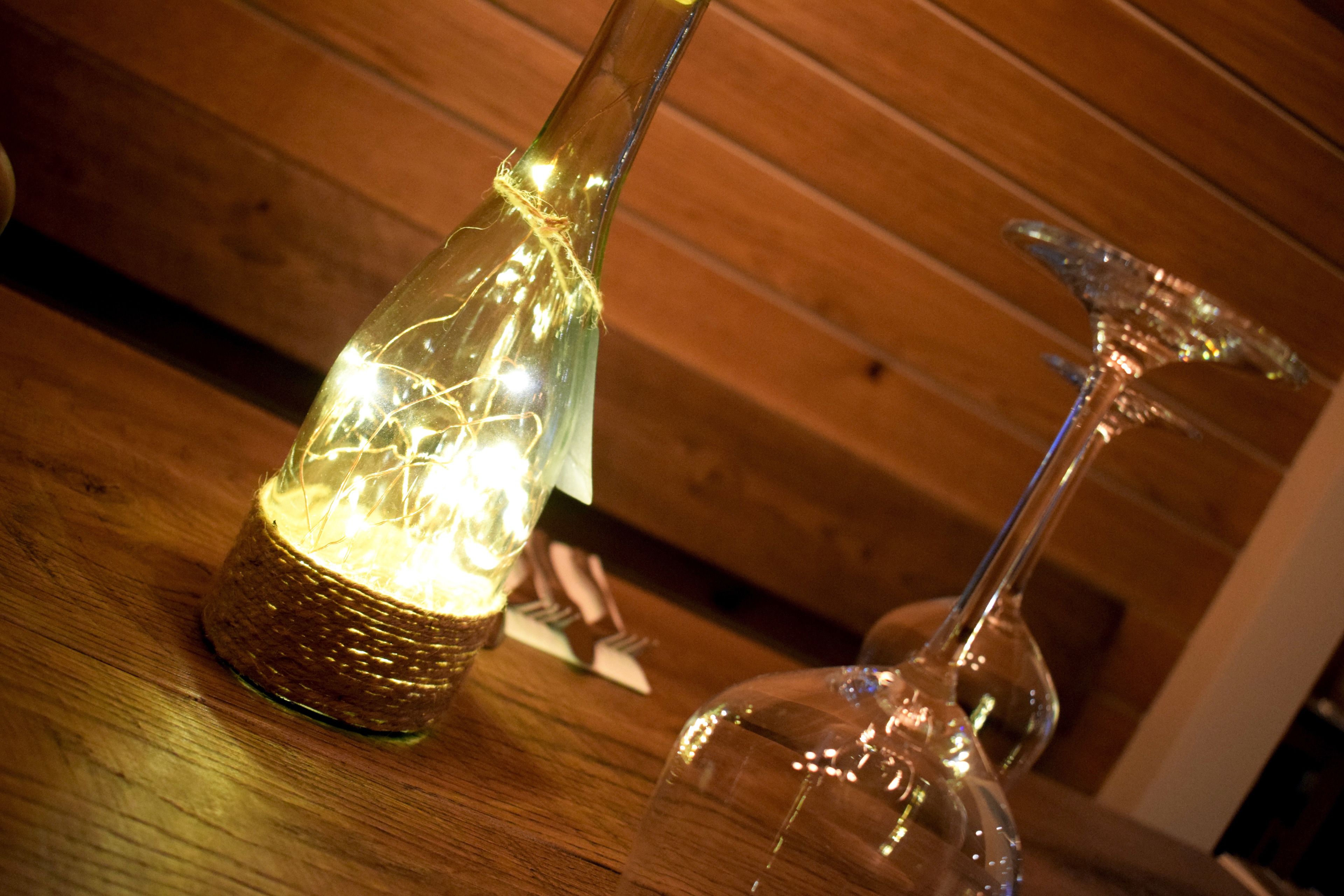 Two glass vases with light bulbs inside, placed on a wooden surface.