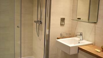 A modern bathroom with a glass-enclosed shower, a white sink, and a toilet.