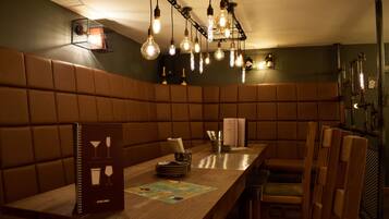 Un restaurante con zona de asientos tipo cabina, una mesa de madera con un menú y lámparas colgantes.