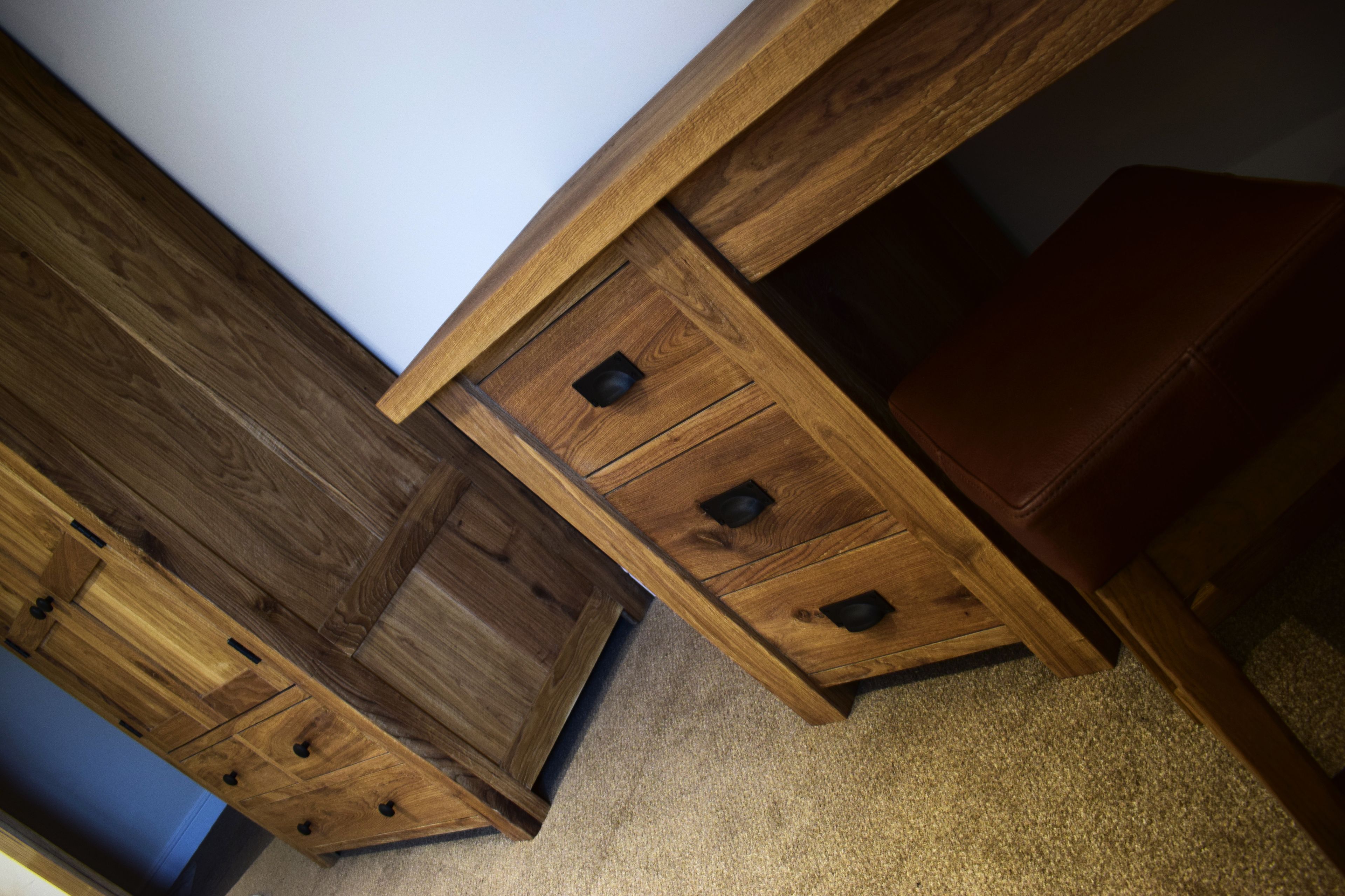 A wooden desk with drawers and a laptop.