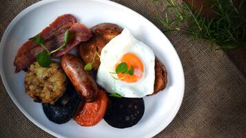 Un plato de desayuno con tocino, salchichas, huevos y tostadas.