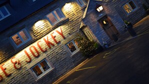 A stone building with illuminated signage reading "The Jockey." - The Horse & Jockey Wessington (Alfreton)