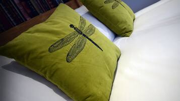 Una cama con dos almohadas, una con un diseño de libélula.