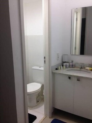 A bathroom with a toilet, sink, and mirror.