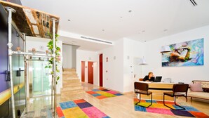 Un vestíbulo de hotel moderno con una escalera, una recepción y una alfombra colorida.