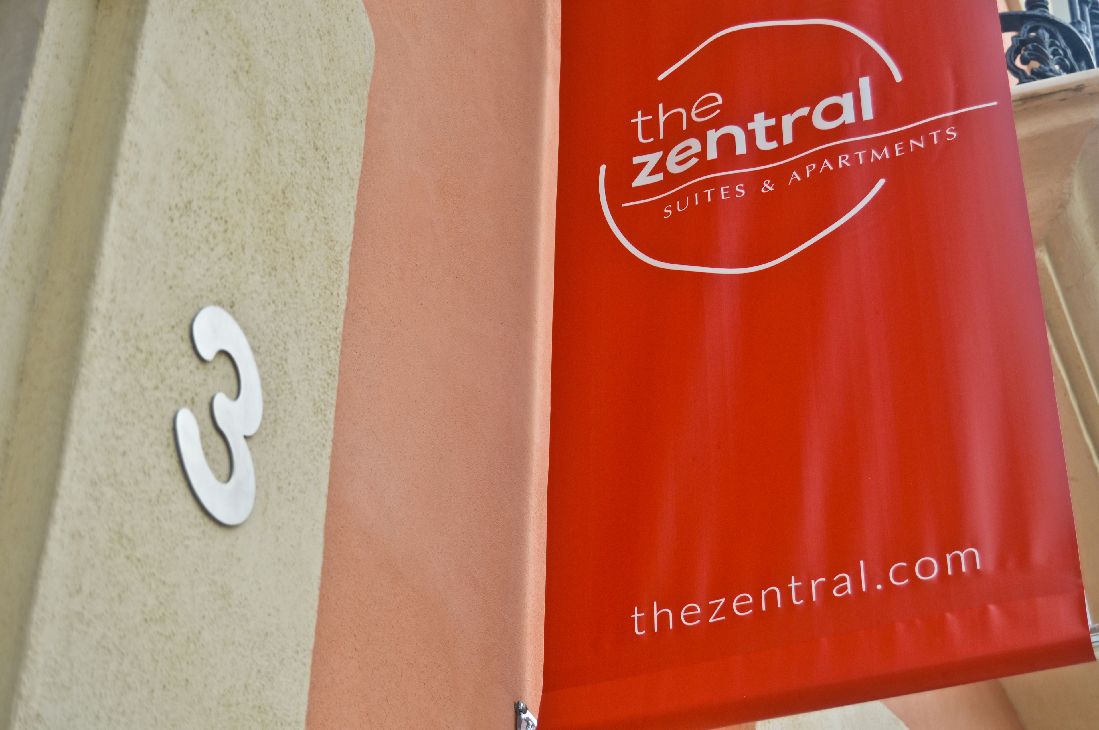 Un letrero rojo con el texto 'the central suites & apartments' y la dirección web thezental.com.