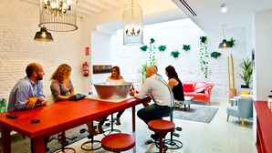 Un comedor moderno con una mesa roja, varias sillas y lámparas colgantes.