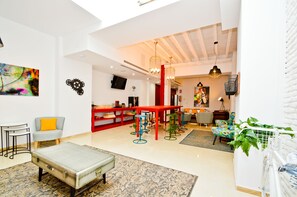 A spacious living area with a red bar, colorful chairs, and a large painting on the wall. - The Zentral Arenal Suites (Seville)