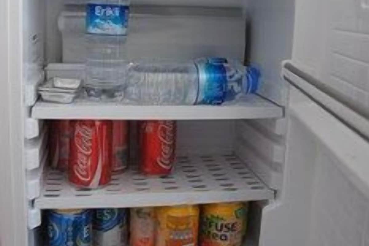 An open refrigerator with water bottles, soda cans, and a carton of juice.