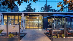 The exterior of SohoBoutique Granada hotel with a glass facade, outdoor seating area, and a signboard. - Hotel Soho Boutique Granada (Granada)