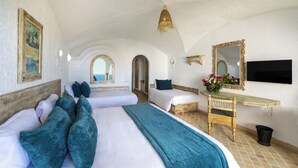Una habitación con dos camas, un aparador de madera, un espejo, un televisor y vistas al mar.