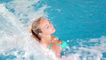 A person in a swimming pool with water splashing around.