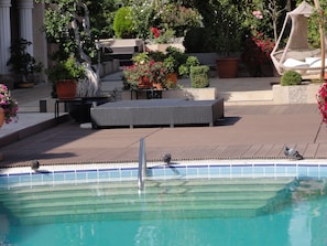 A pool area with a seating area, steps leading into the pool, and surrounding greenery. - Vox Maris Grand Resort - Adults only (Costinesti)
