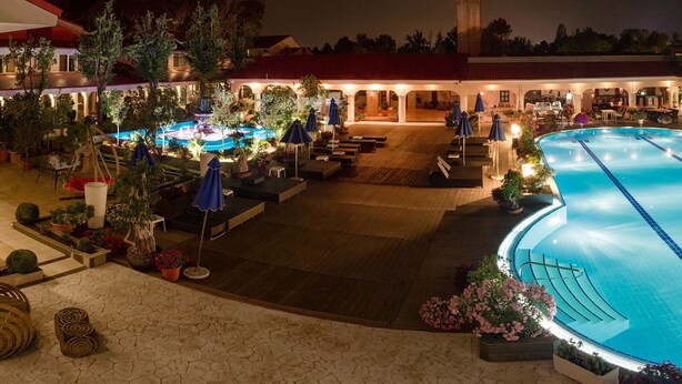 A large indoor swimming pool with multiple lanes, surrounded by outdoor seating areas and a covered patio. - Vox Maris Grand Resort - Adults only (Costinesti)