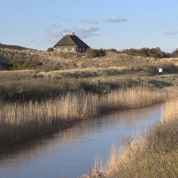 Una casa en una colina con un río al frente.