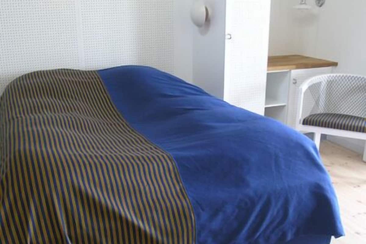 A single bed with a striped blanket and a solid blue cover.