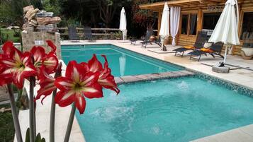 A pool area with lounge chairs and umbrellas, surrounded by a wooden cabin labeled "REST".