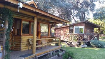 A rustic log cabin with a wooden deck and outdoor seating.