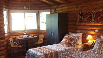 Une chambre aménagée dans un chalet en rondins, avec deux lits, une table à manger et une chaise.