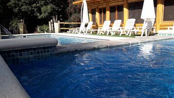 Une piscine à l’eau d’un bleu cristallin, entourée de chaises longues blanches et de parasols.