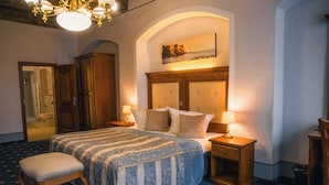 A hotel room with a bed, two bedside tables, a chair, a wooden wardrobe, and a painting on the wall. - Hotel Italia (Görlitz)