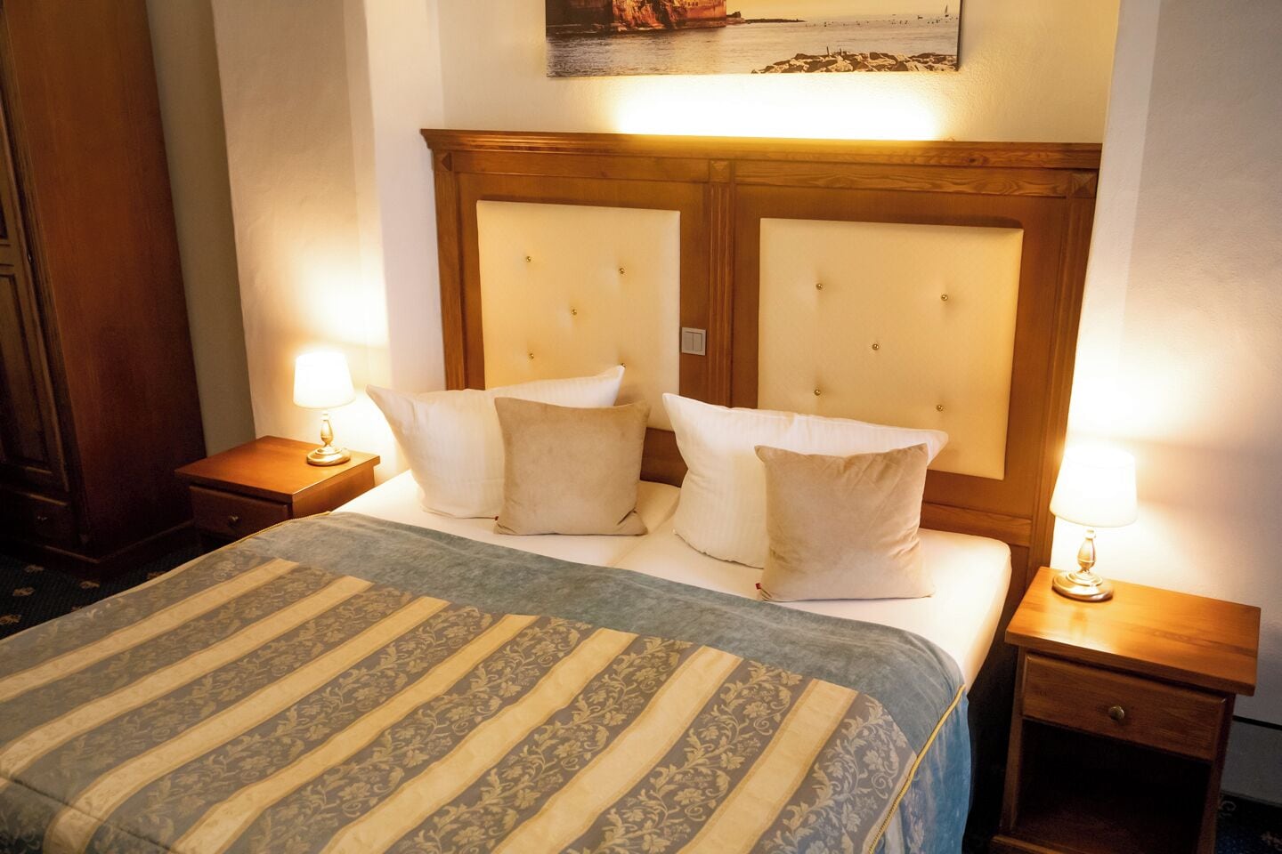 Une chambre d’hôtel avec un grand lit, deux tables de chevet, une tête de lit et un tableau au mur.