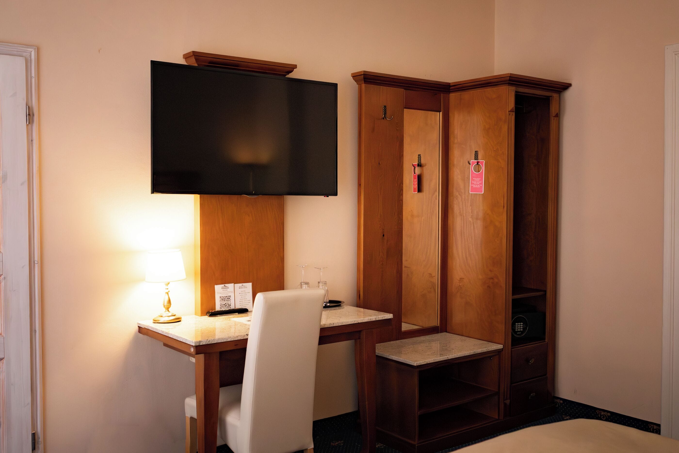 Habitación de hotel con escritorio, silla, televisor y armario.
