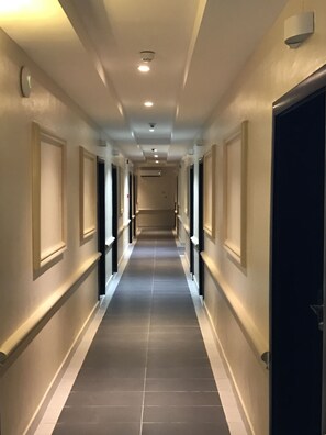 Un pasillo de hotel con diseño largo y estrecho, con puertas a ambos lados y un pasillo central.