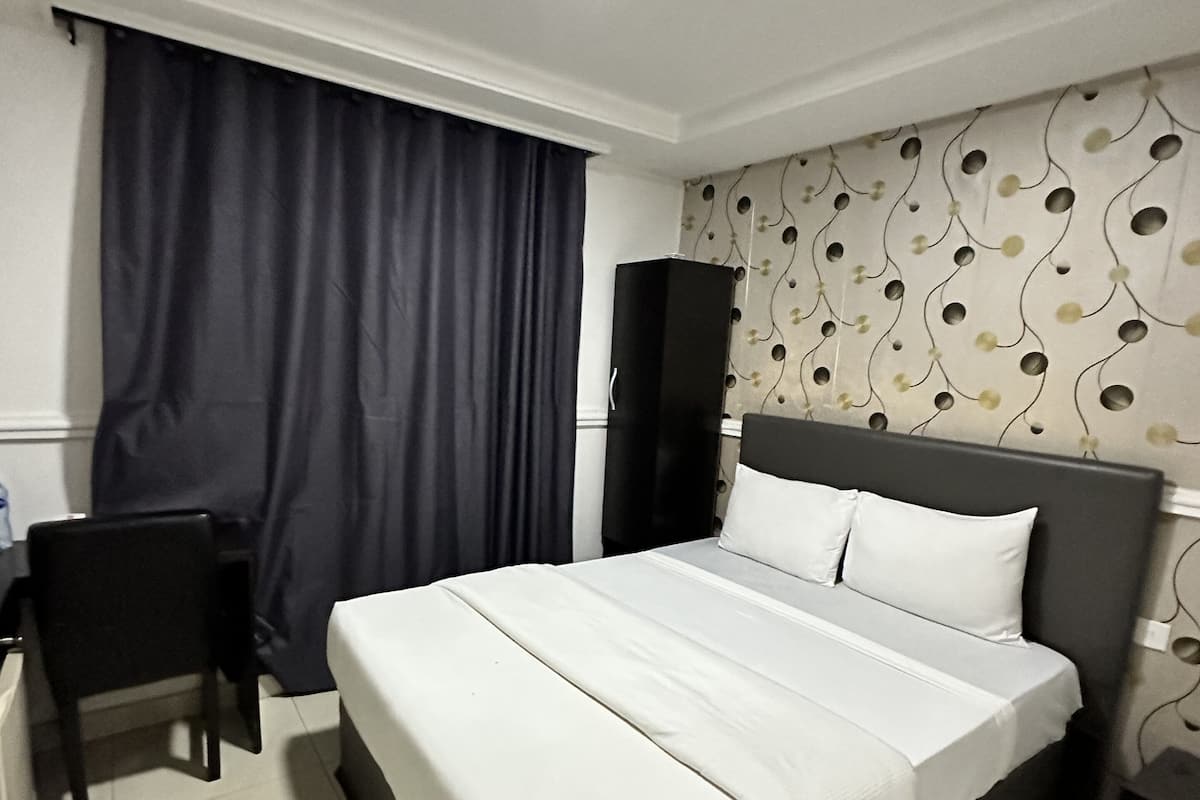 Ein Hotelzimmer mit Bett, Schreibtisch, Stuhl, Kleiderschrank und einer Wand mit Muster.