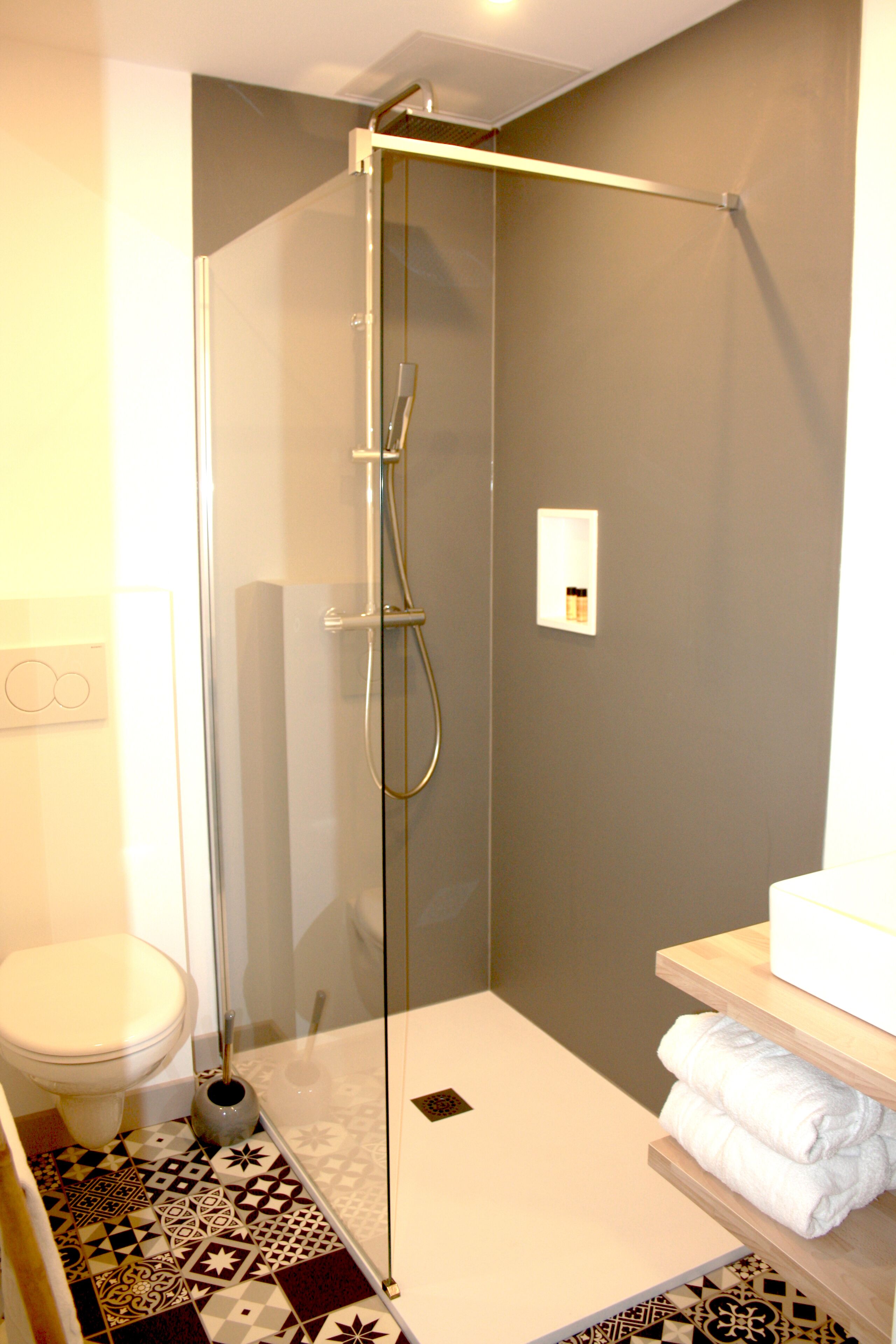 Un baño moderno con ducha acristalada, inodoro y zona de lavamanos con toallas.