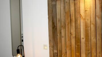 Un dormitorio con cabecera de madera, una lámpara de noche y un espejo en la pared.