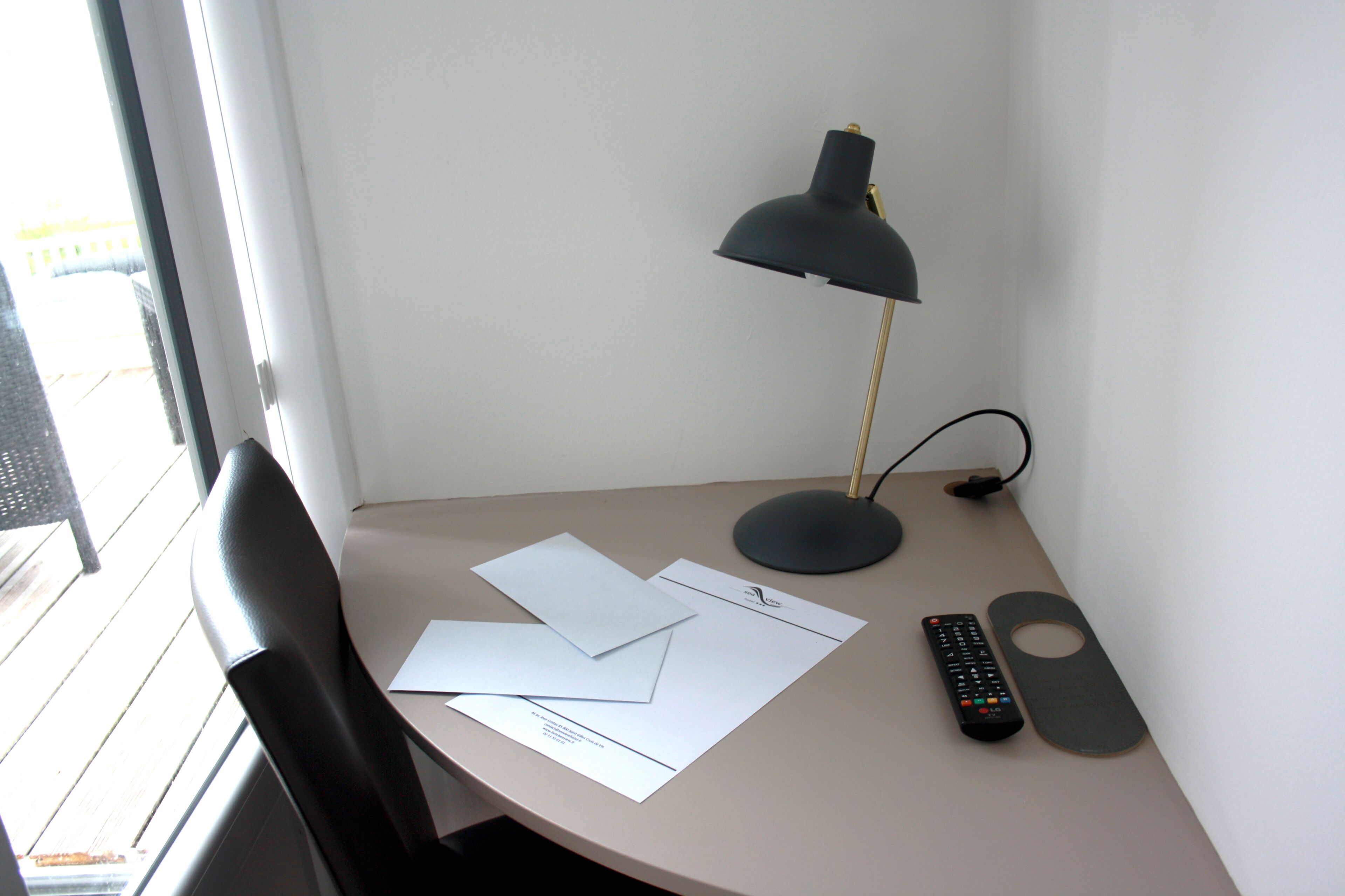 Ein Schreibtisch mit Lampe, Papier, Fernbedienung und Untersetzer.
