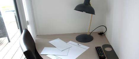 Ein Schreibtisch mit Lampe, Papier, Fernbedienung und Untersetzer.
