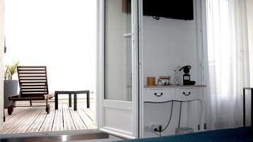 Una stanza con un letto, una scrivania con il telefono e una sedia su un pavimento in legno.