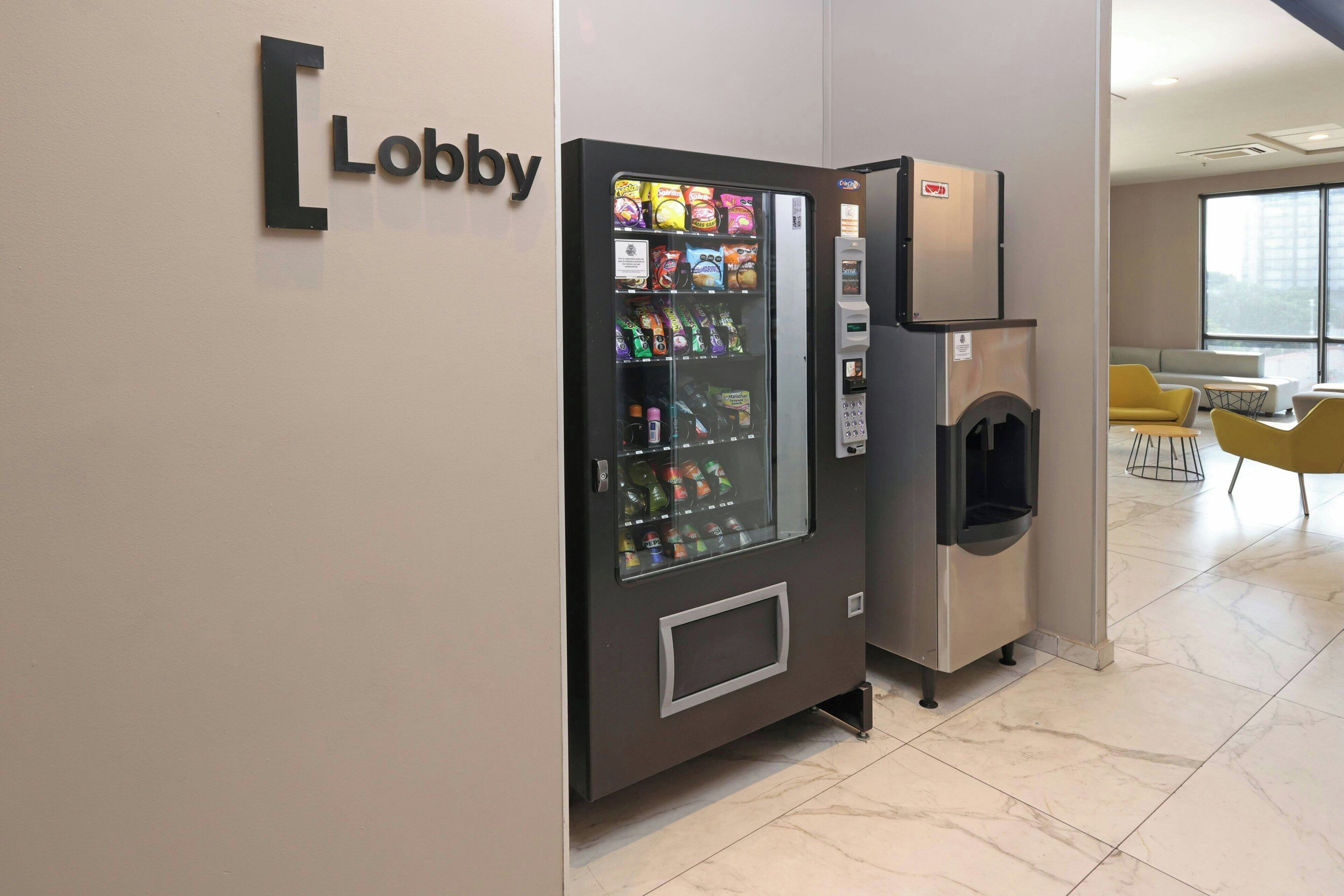 A vending machine with snacks and drinks, a trash bin, and a sign that reads "Lobby".