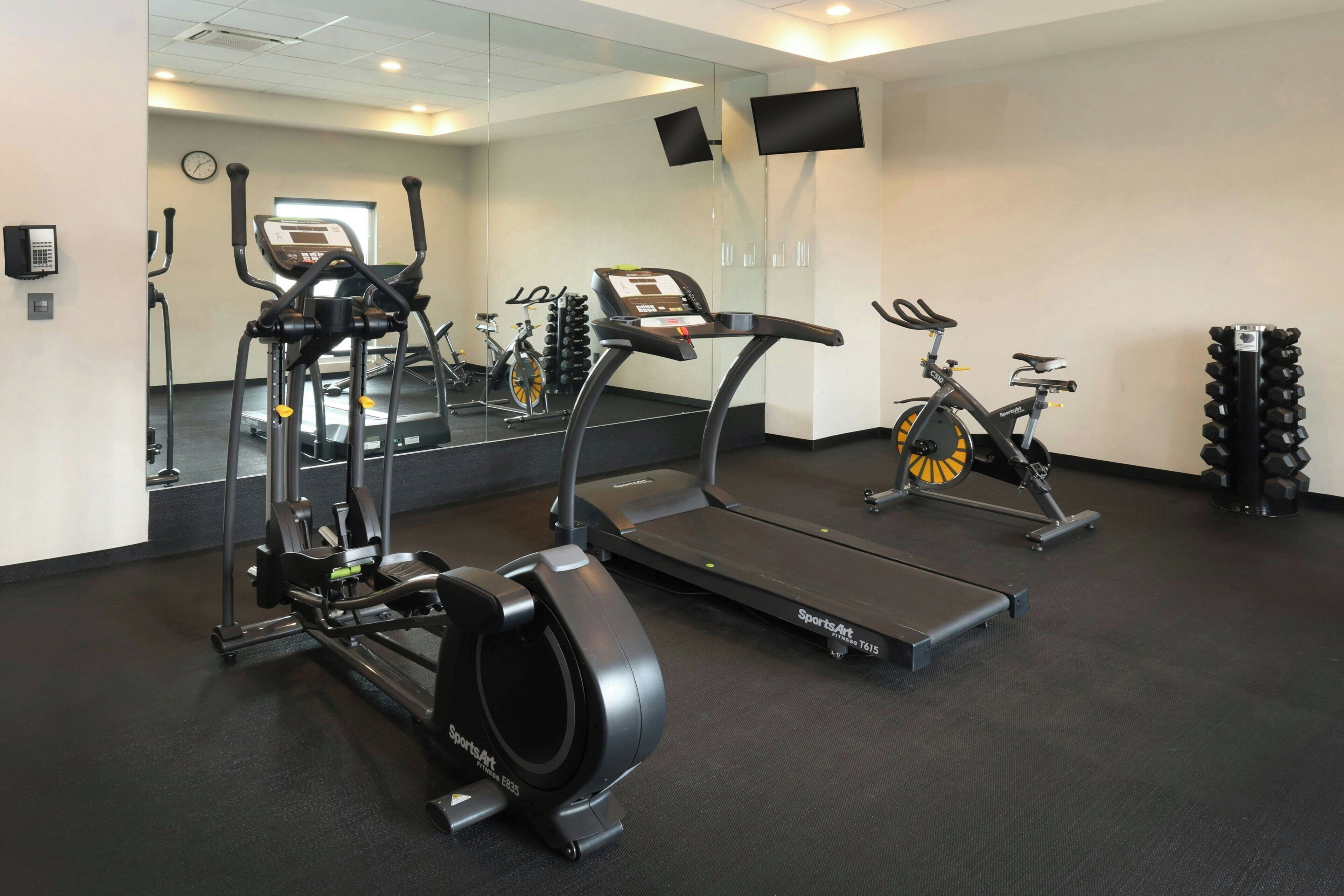 A gym with treadmills, elliptical machines, and a stationary bike.