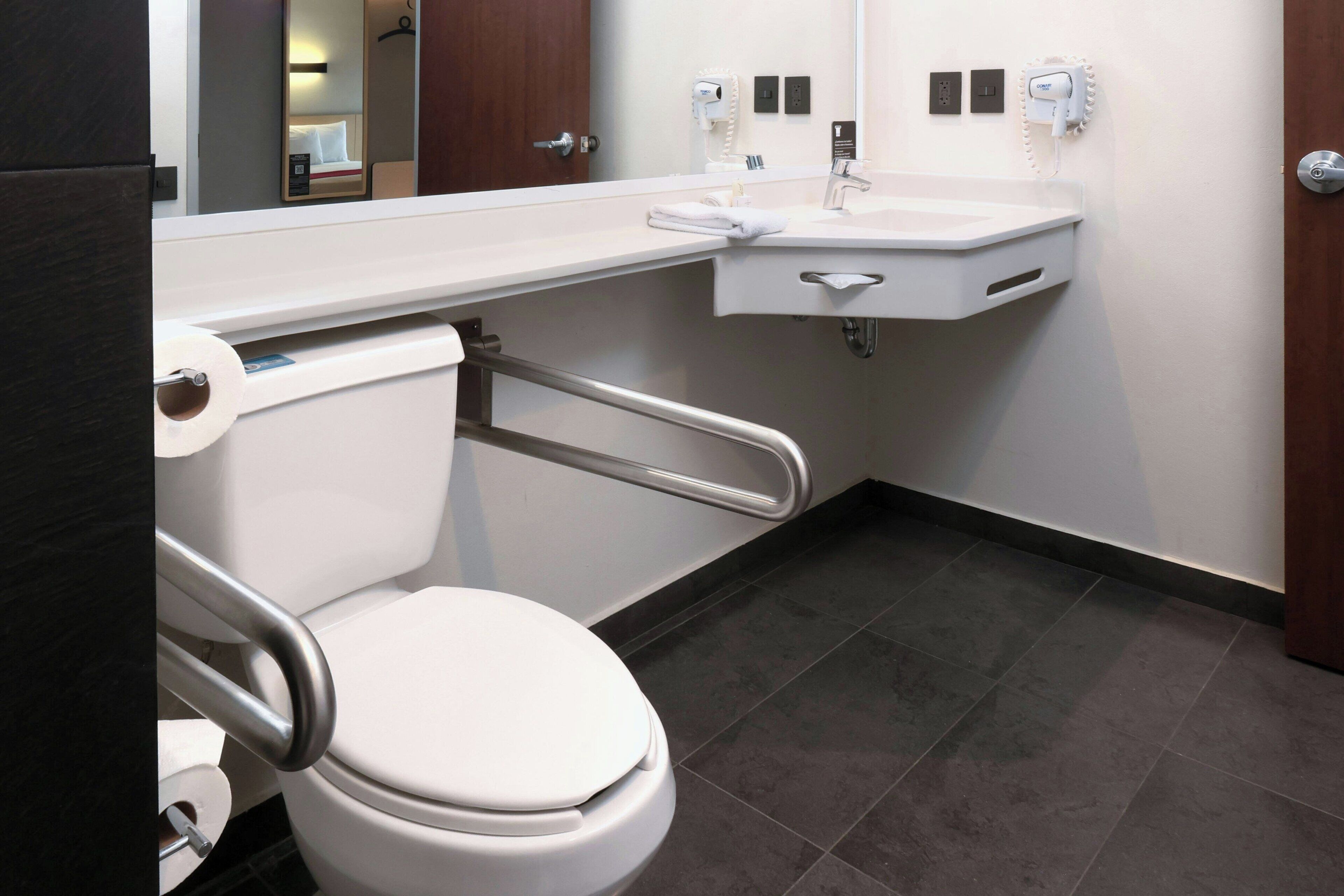 A modern bathroom with a white toilet, a sink, and a mirror.