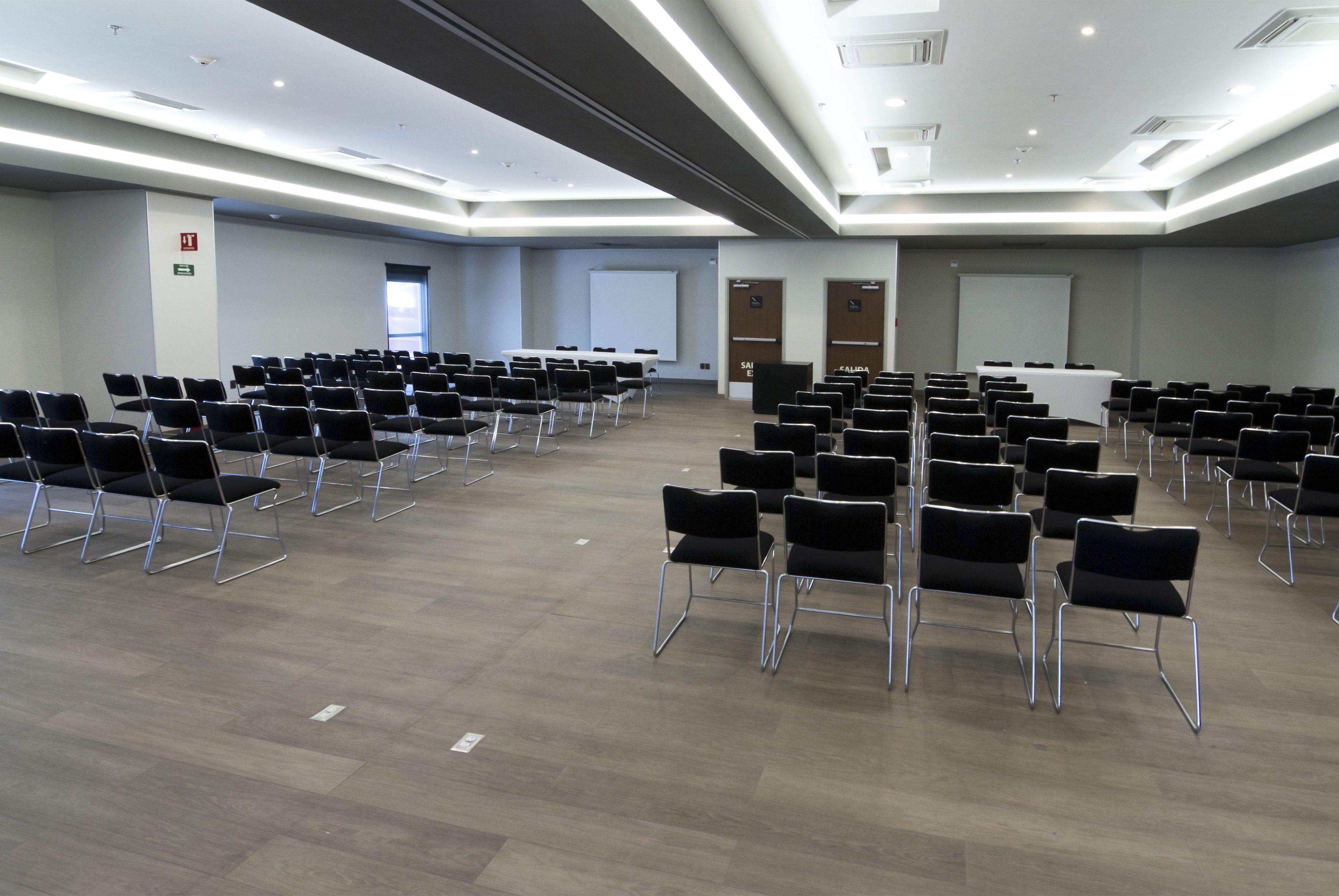 A conference room with rows of chairs, a projector screen, and a whiteboard.