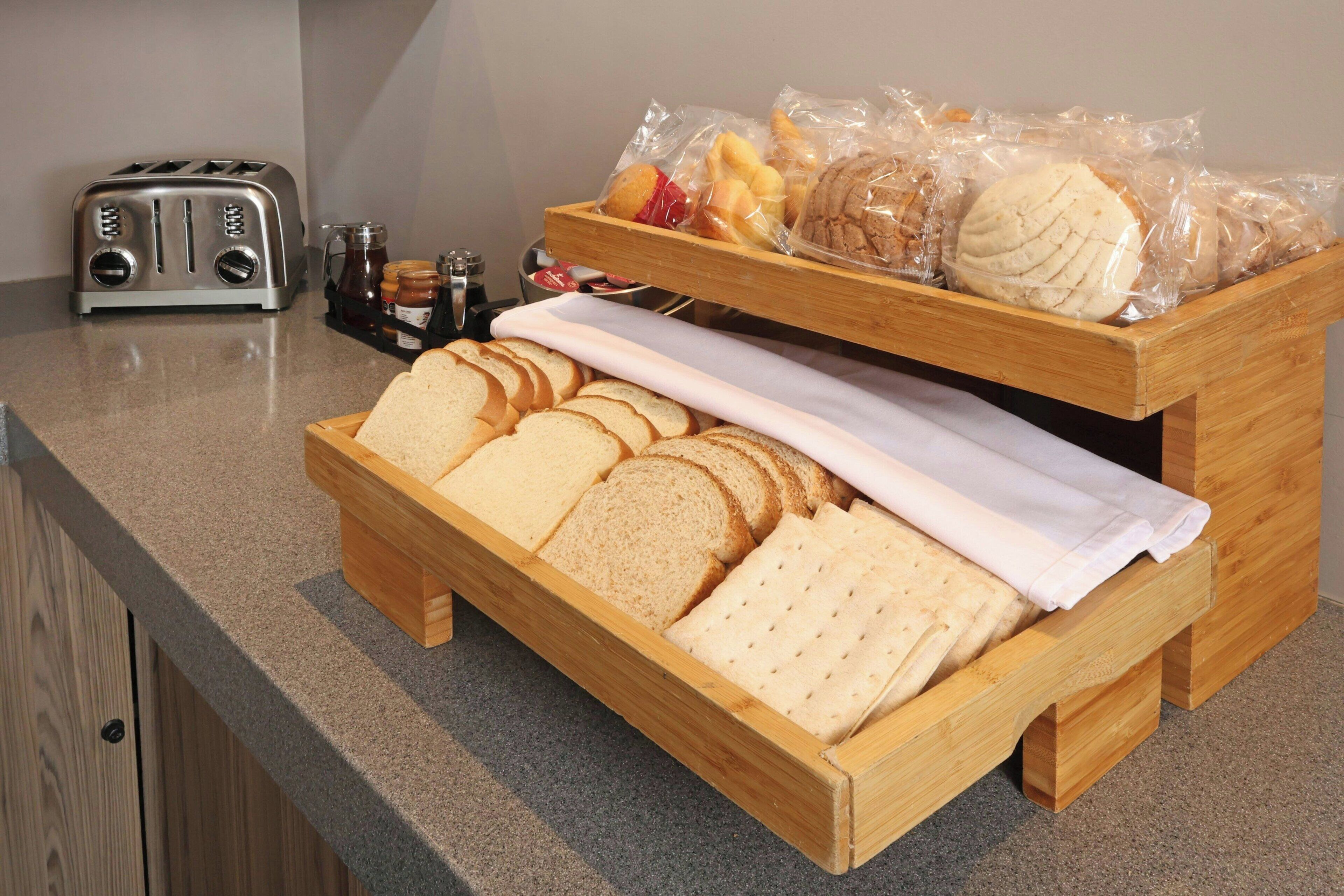 Una cesta de madera con rebanadas de pan y un tostador sobre una encimera de cocina.